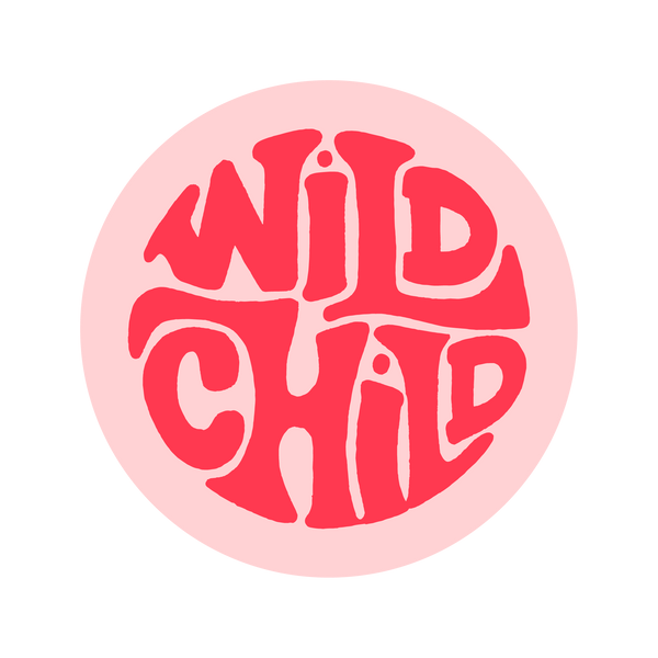 A pink-toned circle sticker with "Wild Child" printed on it in uneven lettering.