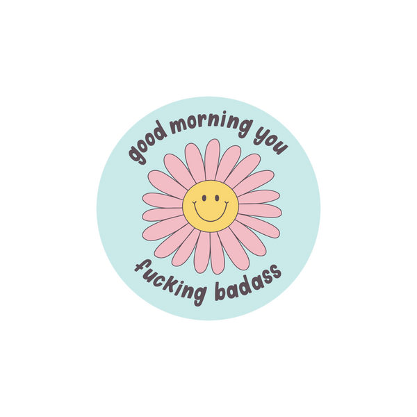 "good morning you fucking badass" sticker with a pink yellow flower in the center on a light blue background.