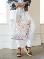 Girl wearing white jeans holding a cute tote bag in white with rainbow confetti pattern.
