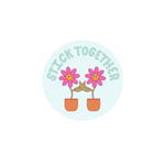 Circle sticker that says Stick Together with two pink flowers holding pedals.