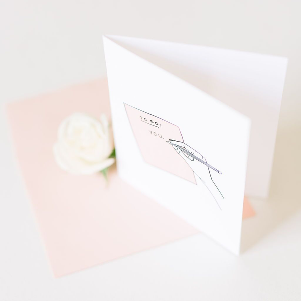 White card with image of peach paper and a hand with a pencil. The paper says "To Do: You"