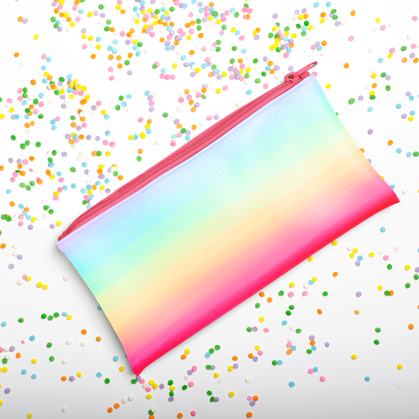 Cute rainbow pencil pouch laying on a bed of sprinkles.