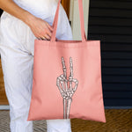 bright coral pink canvas tote bag with skeleton peace sign hand on front.
