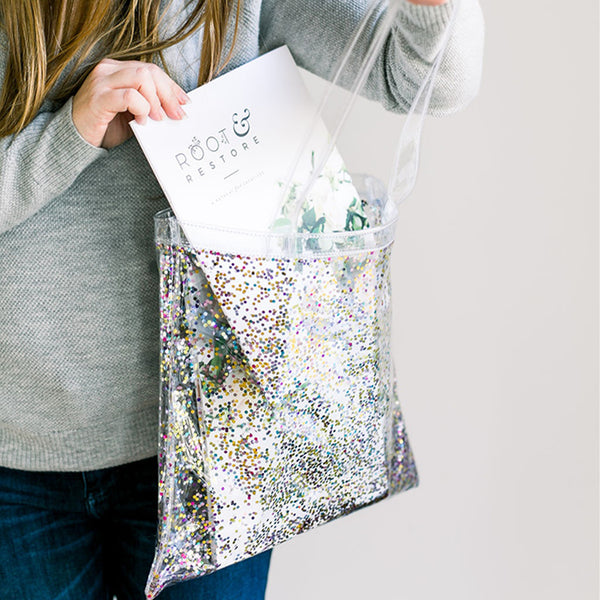 Woman stands with confetti tote, pulling a white magazine out of the tote.