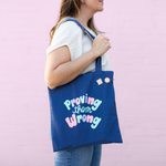 navy tote saying proving them wrong with pins attached over a girls shoulder