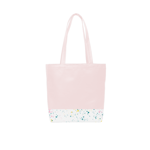 A cute tote bag with long shoulder strap in a blush pink with white paint splatter detail along the bottom.