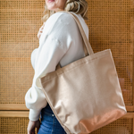 A woman has a metallic gold vegan leather tote bag on her shoulder