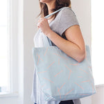 Brunette girl holding a light blue canvas tote bag.
