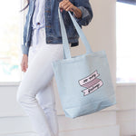 Girl in white jeans holding a cute tote bag in beachwash denim with pink so many feelings banner print.