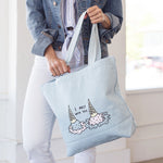Brunette girl in denim jacket holding a denim tote bag with i melt with you double ice cream cones print.