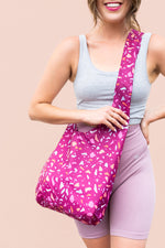 girl wearing a cranberry colored bagabond crossbody tote with pastel speckles