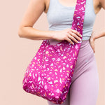 girl wearing a cranberry colored bagabond crossbody tote with pastel speckles