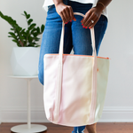 A woman's hands holding a pastel gradient vegan leather tote bag.