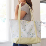 a girl holding a vegan leather weekend bag with white splatter and yellow handles