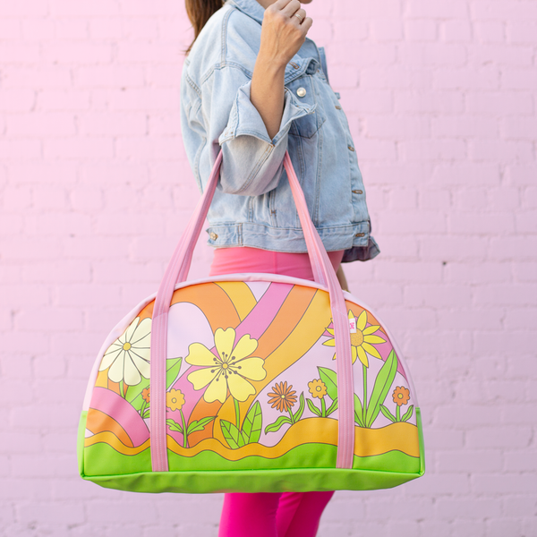 girl holding large tote with pink straps and colorful floral print