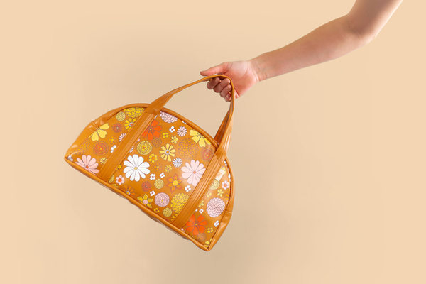 girl swinging bag by handles which is brown ground with fun floral print