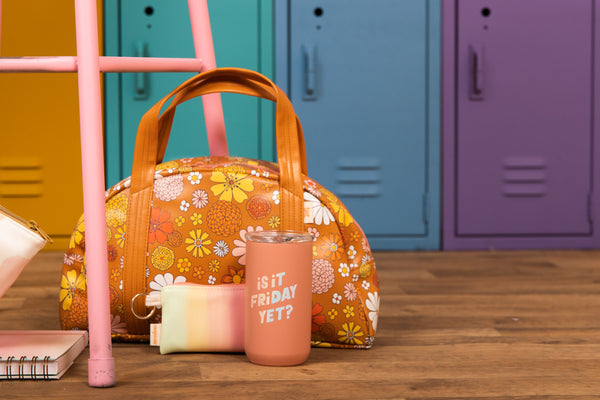 Orange and yellow floral bag in front of colorful lockers and behind "is it friday yet?" cup