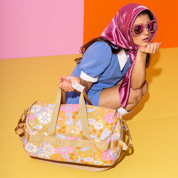 Young lady with sunglasses holding a floral duffle bag.
