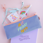 Canvas Pencil Pouch in purple with colorful saying "is it Friday yet?" and a peach zipper. Open with headphones and desk accessories spilling out on top of light purple notebook with "reading is fundamental" on cover.