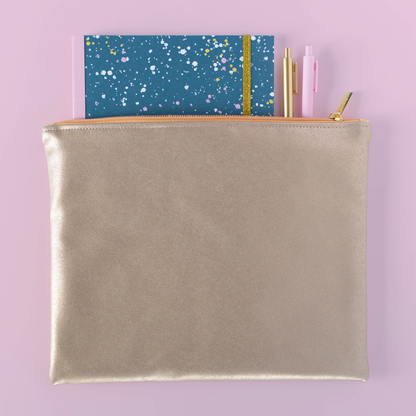 A gold-metallic colored pouch with a terrazzo speckled notebook and two Jotter pens inside the pouch, slightly sticking out.