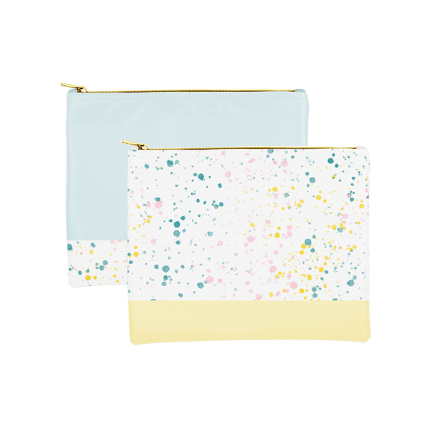 Two large makeup pouches; one white with paint splatter print and a yellow trimmed bottom and the other powder blue with white paint splatter trim along the bottom.