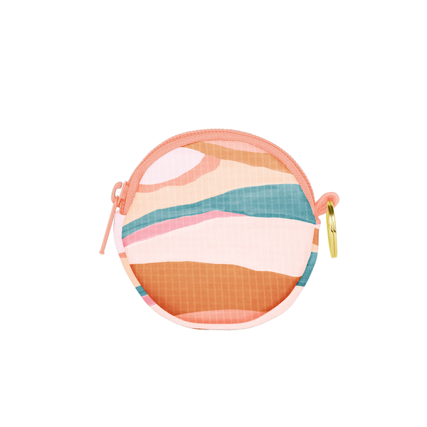 A circle pouch with an abstract hill-like design with neutral and pastel colors. Also has a zipper and key ring.