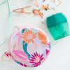 A multicolored, floral circle Dime Piece To-Go pouch with a zipper and keyring.