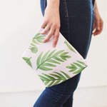 Girl holding a Buds Tweedle Dum, a cute cosmetics bag in blush pink with green leaf pattern.