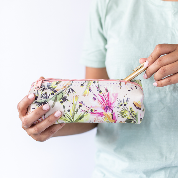 A woman holding a small floral pouch with a gold jotter pen in it. 