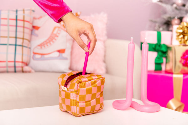 A girl putting a pink pen inside the checkered pouch