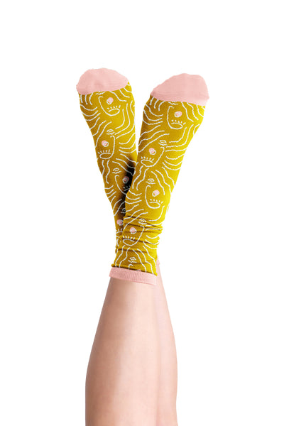 Long socks with Zen Lady design printed on the sock in white. Toes, heel, and top ankle part of the sock is in dusty pink. Socks are displayed on a person with there ankles raises and crossed.