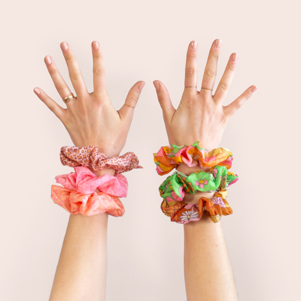 girl with both hands up in air with three rip stop scrunchies on each wrist, left with animal print and right with floral print