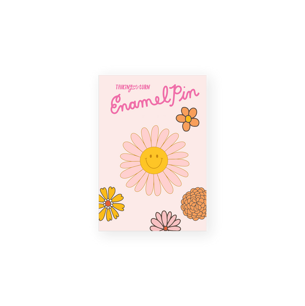 pink daisy enamel pin with yellow smiley face in center