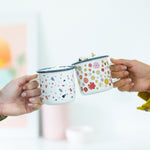 two girls holding cute white mugs with terrazzo and retro floral prints.