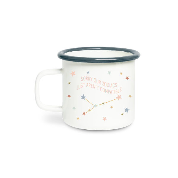 A ceramic white mug with the phrase "Sorry our zodiacs just aren't compatible," in peach colored lettering. Around the phrase are multicolored stars. Rim of mug is a navy blue.