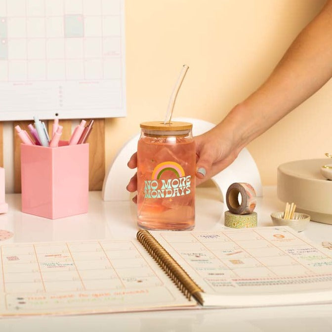 Desk setup with "No More Mondays" can glass w/lid + straw, 2 washi tapes, 1 small monthly planner, and an assortment of TOOT pens. 