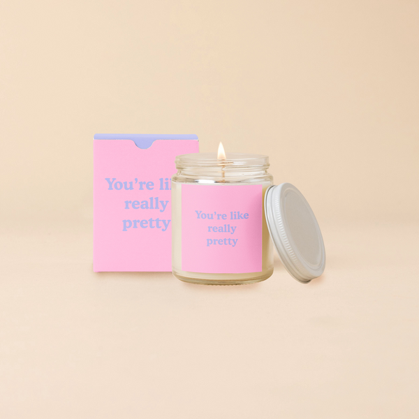 A 8 oz. candle jar with lid, with a pink decal on it "You're like, really pretty" printed on.