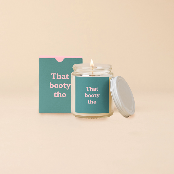 A 8 oz. candle jar with lid, with a teal decal on it "That booty tho" printed on.