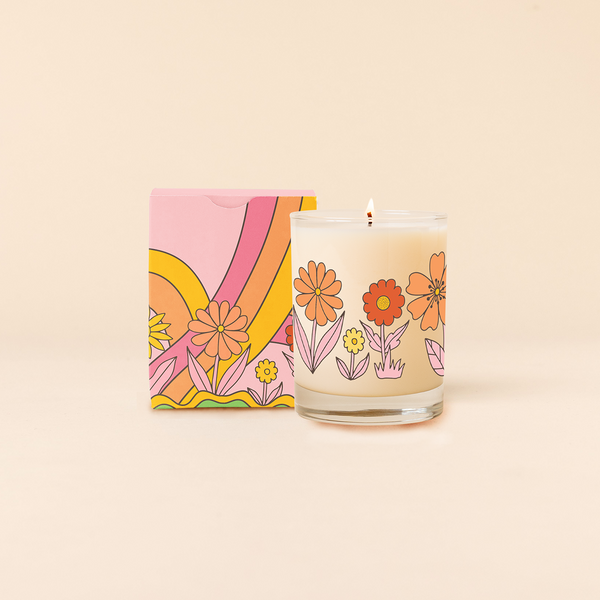 Rocks glass candle with multi-color pastel flowers circling around candle. Multi-color box packaging with tri-color rainbow and same flowers as candle. 