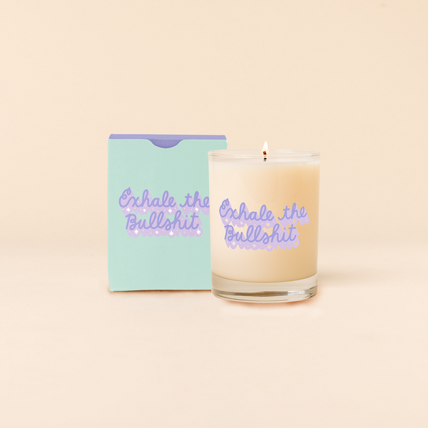 12 oz candle that says "Exhale the Bullshit" in purple cursive lettering.