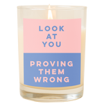 A candle with a decal that says, "Look at you, proving them wrong." Top half is a pastel pink color and bottom half of decal is a dusty blue color.