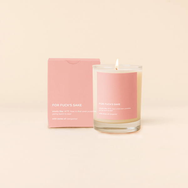 14 oz candle rocks glass with pink decal and text that reads "FOR FUCK'S SAKE; smells like: WTF, how is that even possible, going back to bed; with notes of: bergamont" in white font. Pink box packaging with the same design sits behind the candle.