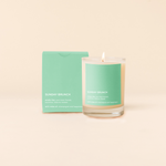 14 oz candle rocks glass with mint green decal and text that reads "SUNDAY BRUNCH; smells like: your best friends, sunshine, hakuna matata; with notes of: champagne and happiness" in white font. Mint green box packaging with the same design sits behind the candle.