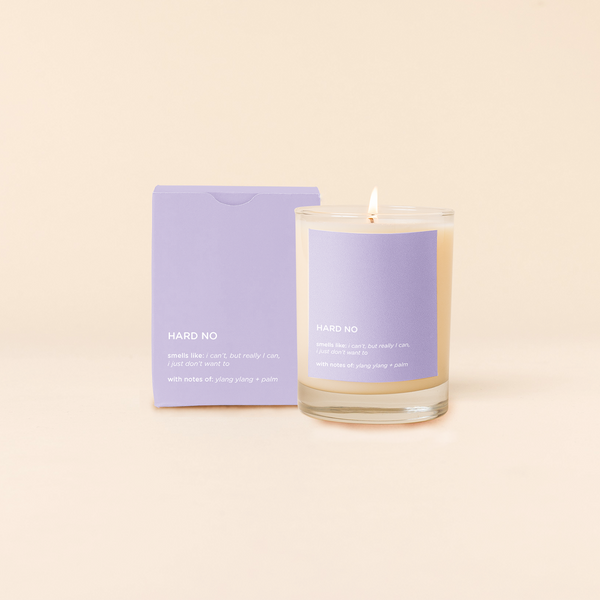 14 oz candle rocks glass with lavender decal and text that reads "HARD NO; smells like: i can't, but really i can, i just don't want to; with notes of: ylang ylang + palm" in white font. Lavender box packaging with the same design sits behind the candle.