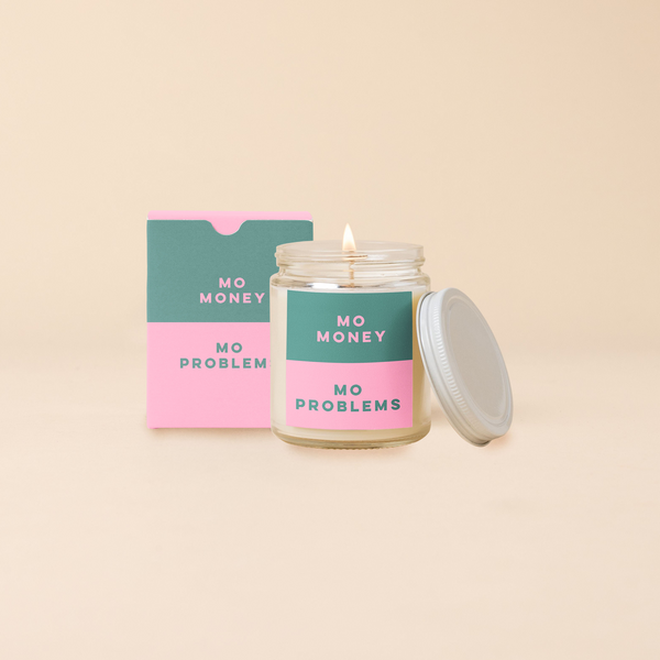 An 8 oz. candle w/ a lid and a split-colored decal (Green and Pink) with the phrase, "Mo money mo problems" printed on.