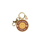 Gold key charm with a neutral brown background, yellow smiley face, and pink flowers with "Fuck Around & Find Out" on it.