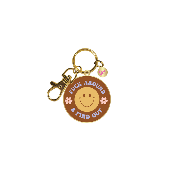 Gold key charm with a neutral brown background, yellow smiley face, and pink flowers with "Fuck Around & Find Out" on it.