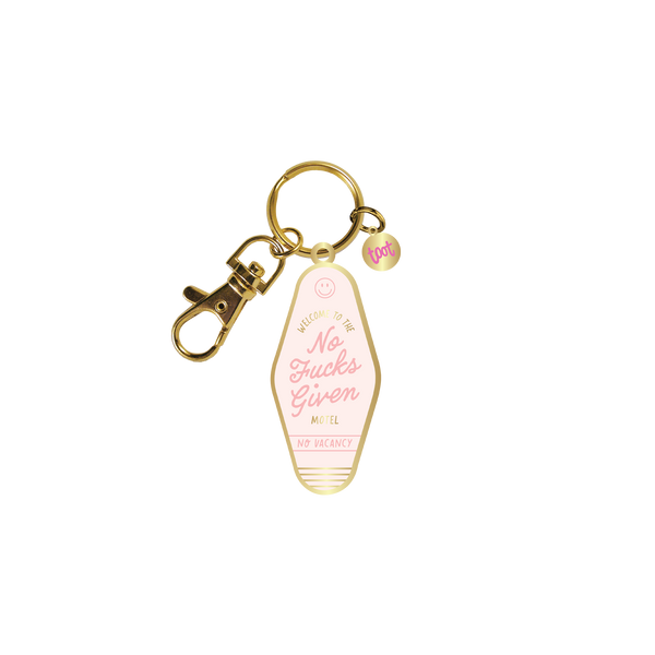 Gold key charm in the shape of a motel key holder with a baby pink background. In a slightly lighter pink "No Fucks Given" is printed while "No Vacancy" in below it. The words "Welcome To The Motel" in gold surround "No Fucks Given."