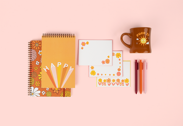 cute set of notebooks one with flowers, one saying happy with a set of letterpress notecards with flowers, set of pens and a brown diner mug with the saying fuck it with sunshine