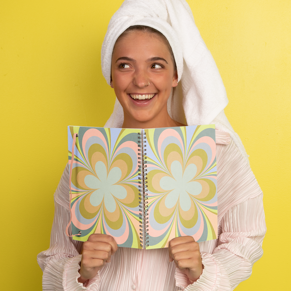 Pastel green background with a girl holding a kaleidoscope floral notebook 